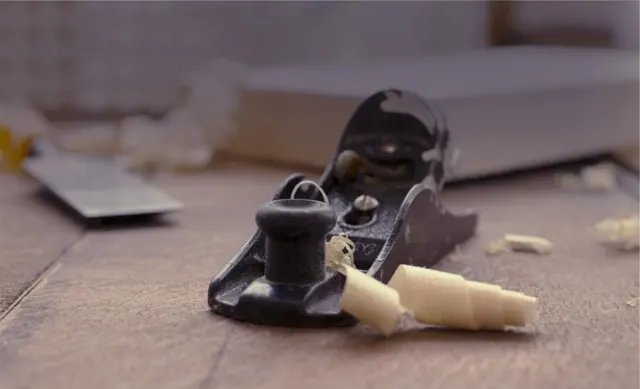 Hand plane and fresh wood shavings on a workbench