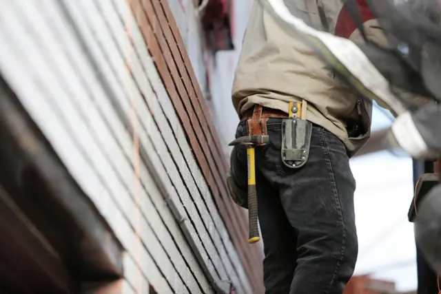 Installer with a tool belt next to wall panels